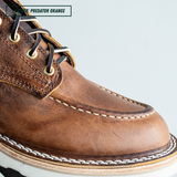 Close-up of a brown leather lace-up boot with white contrast stitching and black laces, labeled 'LEATHER - PREDATOR ORANGE' against a light gray background.