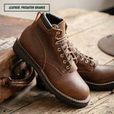 A pair of brown leather lace-up boots with white stitching and metal eyelets, photographed on a rustic wooden surface next to a vintage leather case. A text label in the top left reads 'LEATHER: PREDATOR ORANGE'.