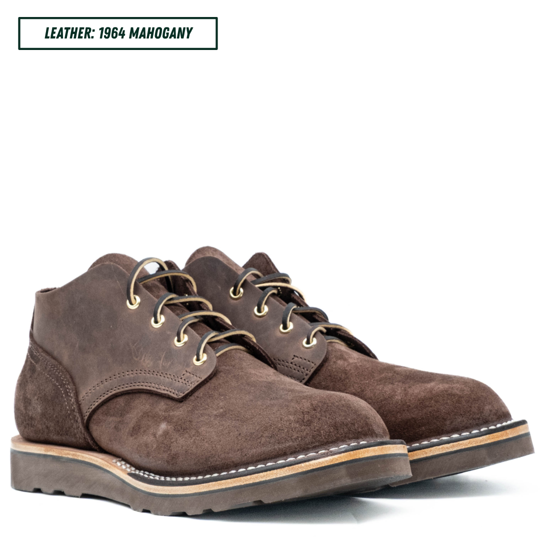 A pair of dark brown suede lace-up boots on a white background, with a text label in the top-left corner reading 'LEATHER: 1964 MAHOGANY'.