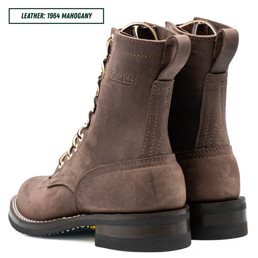 A pair of brown suede lace-up boots shown from the side and back on a white background, with a text label in the top-left corner reading 'LEATHER: 1964 MAHOGANY'.