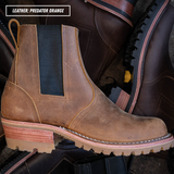A brown leather Chelsea-style boot with a dark elastic side panel and a chunky lug sole, shown in front of other boots. A text label in the top left reads 'LEATHER: PREDATOR ORANGE'.