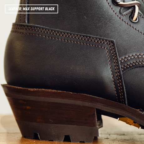 Close-up of a black leather lace-up boot heel and sole, showing dark brown stitching and a dark brown stacked heel. Text overlay in the top left reads 'LEATHER: MAX SUPPORT BLACK'.