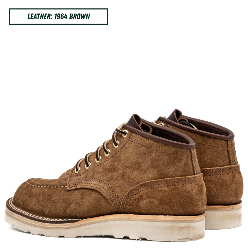 A pair of men's lace-up ankle boots in brown suede, shown from a three-quarters angle. A text overlay in the top left corner reads 'LEATHER: 1964 BROWN'.