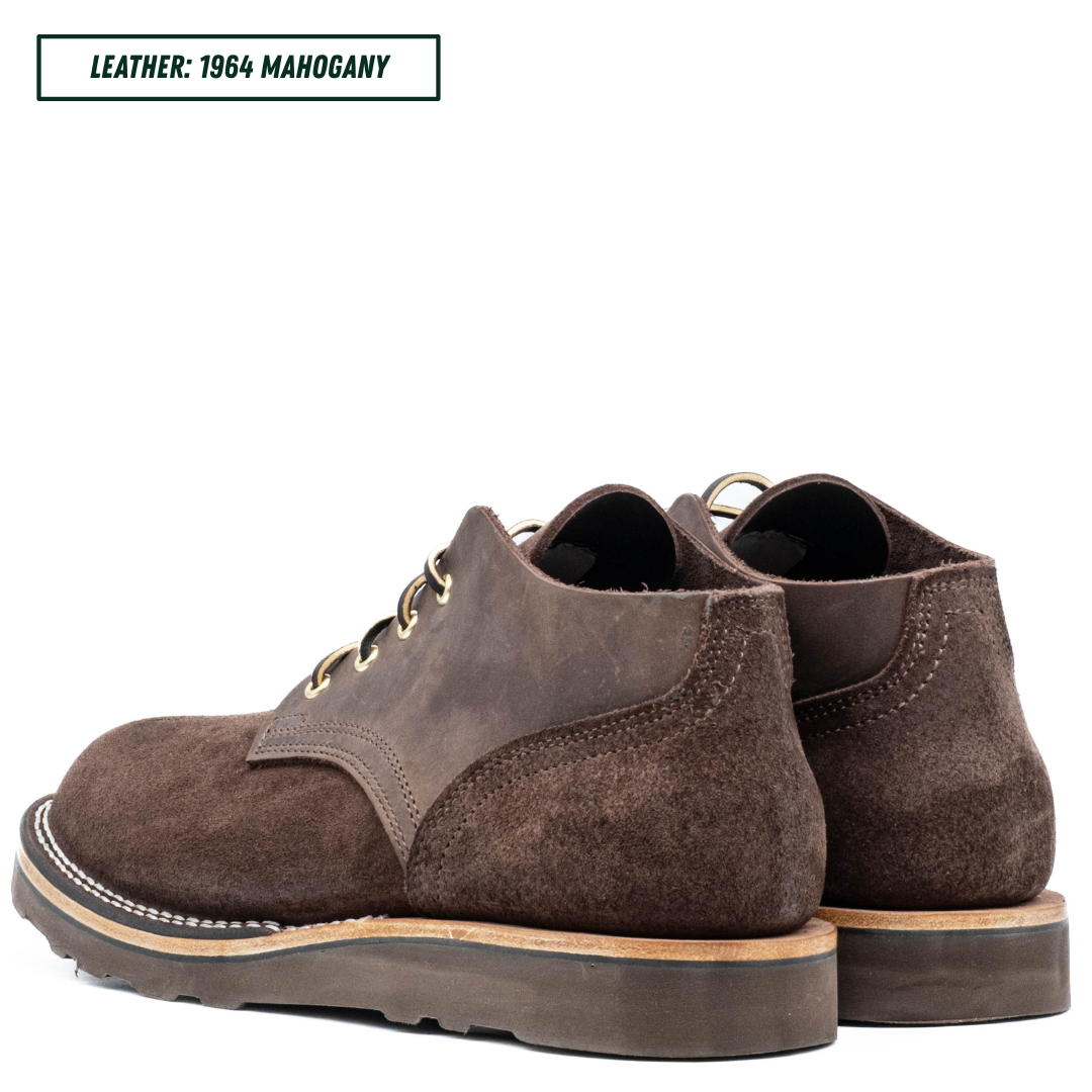 A pair of dark brown suede lace-up boots shown from the side and back on a white background, with a text label in the top left reading 'LEATHER: 1964 MAHOGANY'.