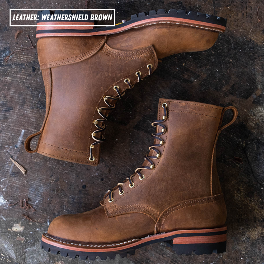 Two brown leather lace-up boots arranged on a dark rustic wooden surface. One boot is upright and the other is angled on top, showing the side, front lace area, heel, and sole.