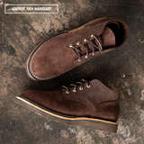 Two dark brown suede lace-up shoes arranged on a textured dark surface. One shoe is shown from the side/top and the other from the bottom/side.