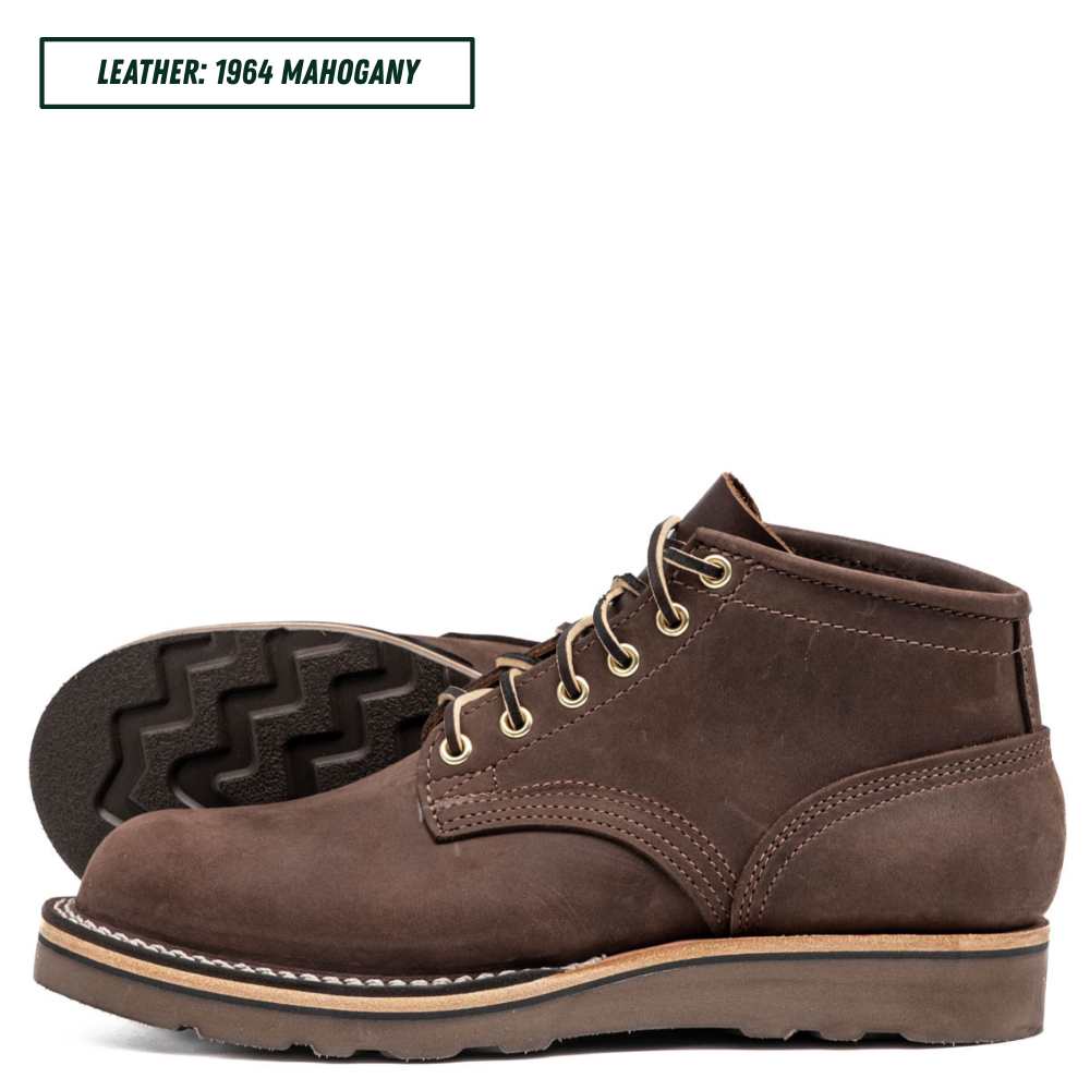 A pair of dark brown leather lace-up boots shown on a white background, with one boot standing upright and the other lying on its side to display the tread. A text label in the top left reads 'LEATHER: 1964 MAHOGANY'.