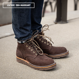 A person wearing dark brown suede lace-up boots with blue jeans, standing on a concrete surface. A text label in the top-left corner reads 'LEATHER: 1964 MAGOHANY'.