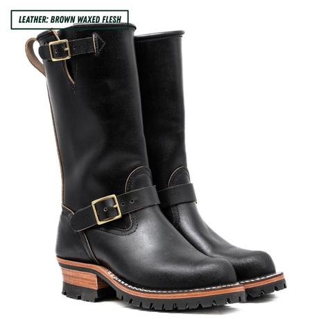 A pair of black leather mid-calf boots with brown waxed-flesh stacked heels and gold-tone buckle straps, shown on a white background with a text label in the top left corner.