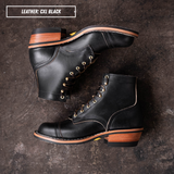 A pair of black leather lace-up ankle boots with gold-tone eyelets and stacked brown and black soles, arranged on a dark textured surface. A text label in the top left reads 'LEATHER: CXL BLACK'.