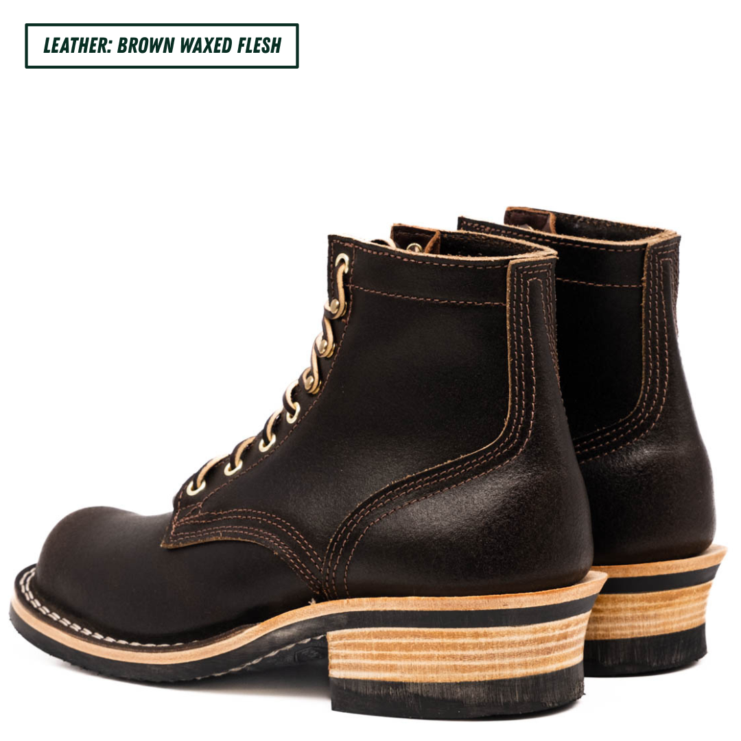 A pair of dark brown leather lace-up ankle boots with stacked wood-look heels, shown from a three-quarters angle on a white background. A text label in the top-left corner reads 'LEATHER: BROWN WAXED FLESH'.