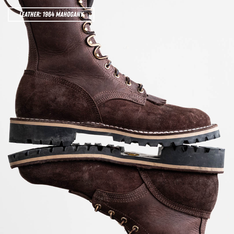 A pair of dark brown leather lace-up boots stacked vertically, with one boot upright and the other lying flat to show the sole. The boots feature a textured leather upper, metal eyelets, and thick black lug soles with a beige stripe.