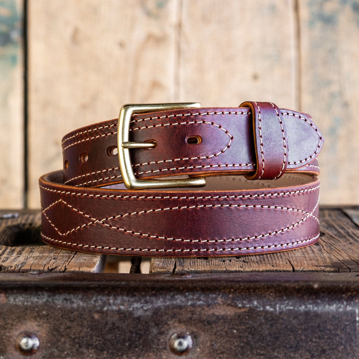 Brown leather belt with gold buckle on a wooden surface