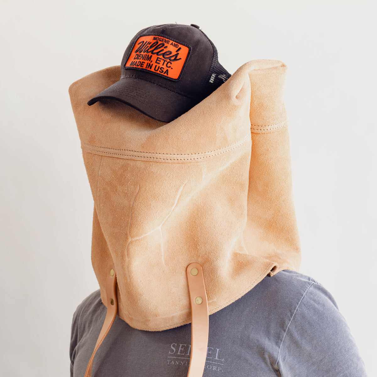 Model wearing Veg Tan Suede Tote with no pocket, showing cattle brand on his head with hat on top.