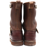 A pair of dark brown leather boots shown from the back, featuring pull tabs and buckle straps, set against a plain white background.
