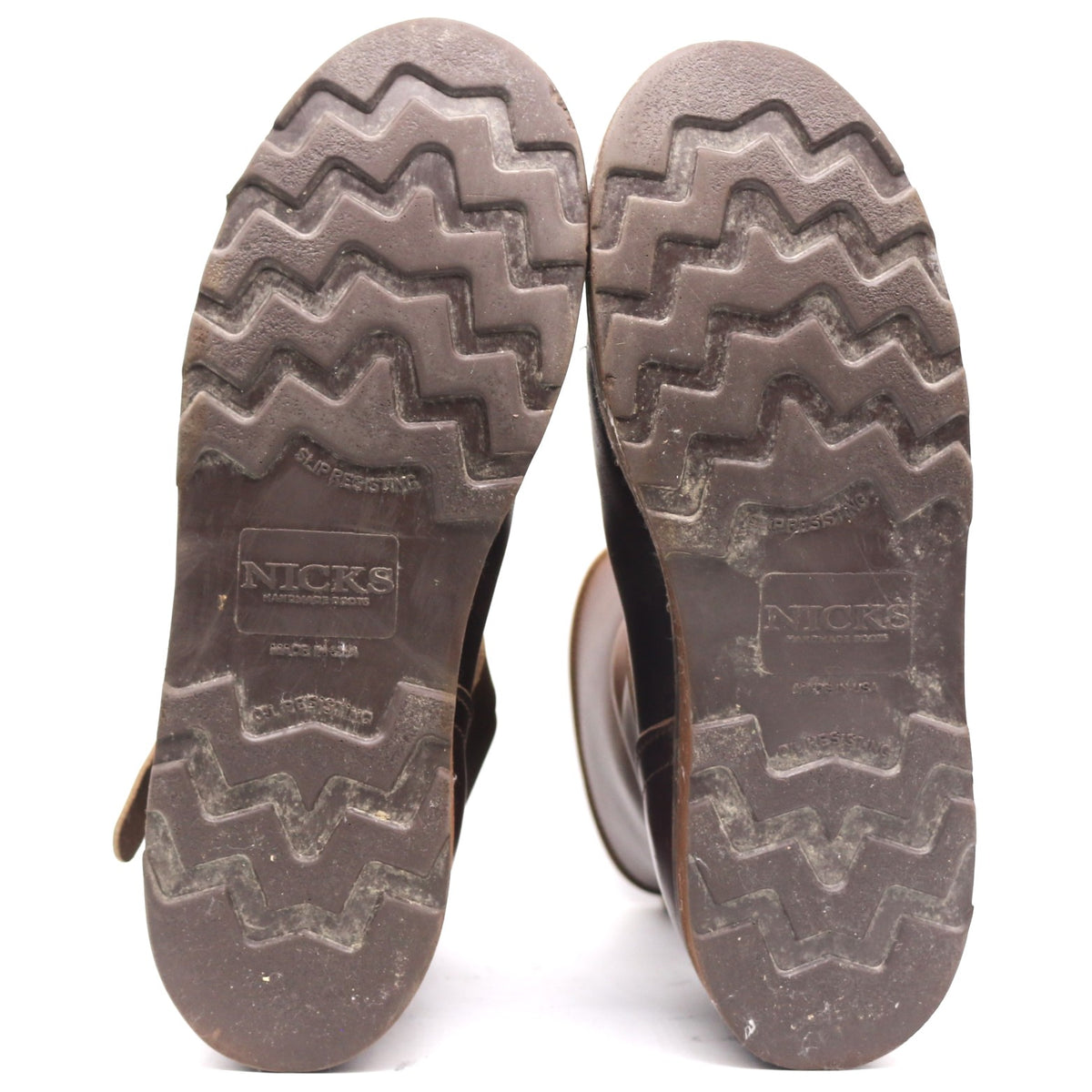 The soles of a pair of boots, showing the zig-zag tread pattern and the embossed brand name 'NICKS'.