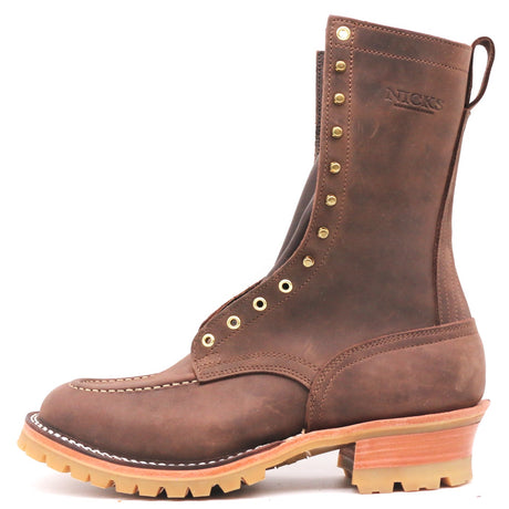 A brown leather lace-up work boot with brass eyelets, a pull tab, and a stacked tan and orange-brown sole, shown on a white background. The brand name 'NICKS' is embossed on the side.