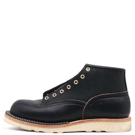 A single black leather high-top work boot with gold-tone metal eyelets, contrast stitching, and a thick off-white sole, shown from a side profile on a white background.