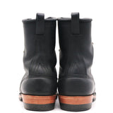 A pair of black leather work boots shown from the back, featuring pull tabs at the top and a brown wooden-look midsole.