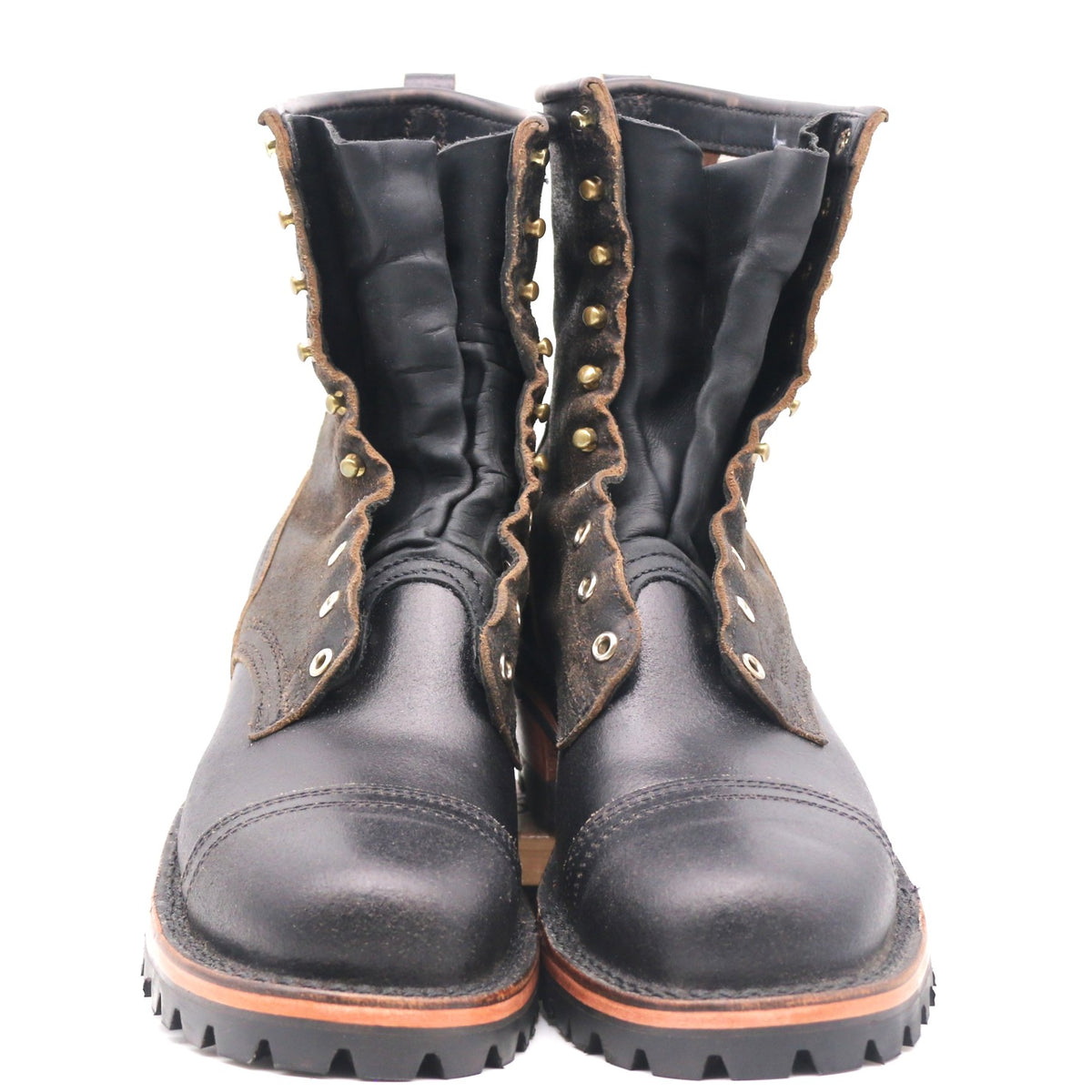 A pair of black leather lace-up boots with brown suede side panels, brass eyelets, and a rugged black sole, shown against a plain white background.