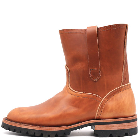 A single mid-calf leather boot in a warm cognac brown, featuring a pull strap on the side, a rugged black lug sole, and contrast stitching, shown against a plain white background.