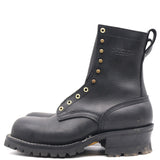 A black leather work boot with gold-tone metal eyelets and studs, featuring a pull tab and a rugged lug sole, shown from a side profile on a white background.