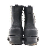 A pair of black leather lace-up ankle boots shown from the back, featuring brass grommets and thick lug soles, set against a plain white background.