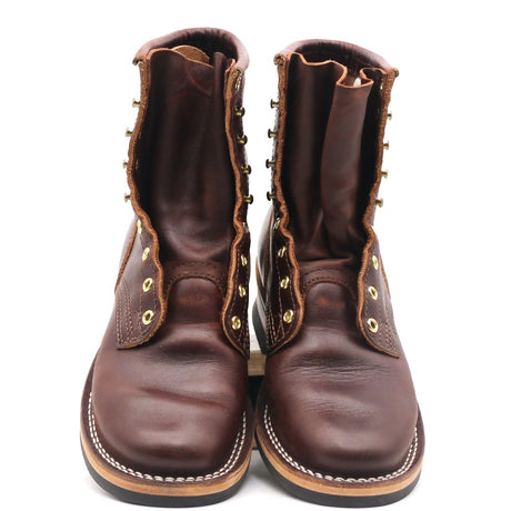 Front view of unlaced dark brown leather lace-up work boots with brass eyelets and white welt stitching