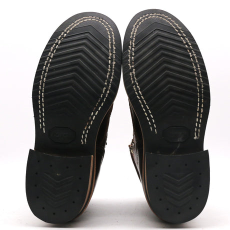Black textured rubber outsoles with chevron tread white stitching and nailed heels on handmade boots