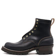 A black leather ankle boot with gold-tone metal eyelets, a dark brown lug sole, and a pull tab on the heel, shown from a side profile on a white background.