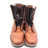 A pair of mid-calf work boots in tan leather with dark brown leather shafts and black metal eyelets, shown from the front on a white background.