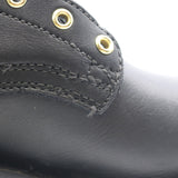 Close-up of a black leather boot showing the side panel with gold-tone metal eyelets and stitching.