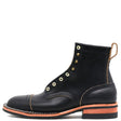 A single black leather lace-up ankle boot with brass eyelets, contrast stitching, and a stacked black sole with a bright orange-red midsole layer, shown against a plain white background.