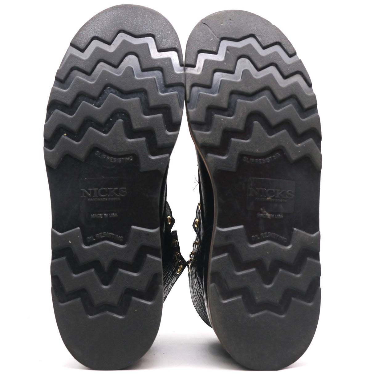 The treaded black rubber soles of a pair of boots, shown from the bottom against a white background. The brand name 'NICKS' is embossed on the center of each sole.