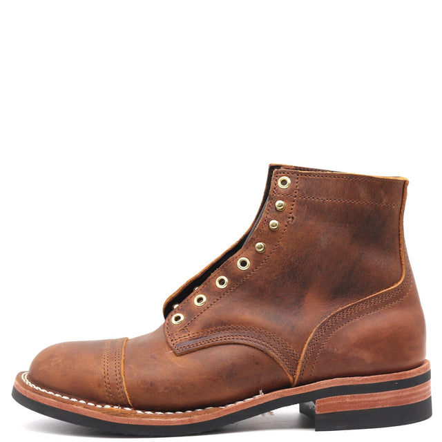Brown ankle boot with brass hardware in front of a while background.