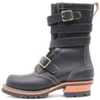 A black leather mid-calf boot with double buckle straps, contrast white stitching, and a stacked lug sole with a tan and black heel, shown against a plain white background.