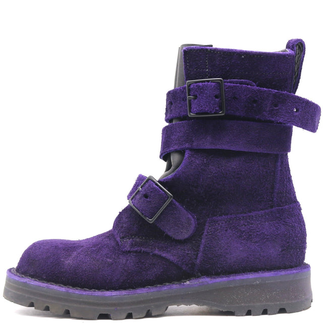 A single purple suede ankle boot with two adjustable strap closures and black buckles, shown from a side profile on a white background.