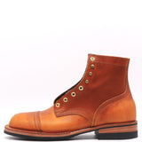 A single leather ankle boot in a warm cognac brown, featuring brass grommets, a cap toe, and a black sole, photographed against a plain white background.
