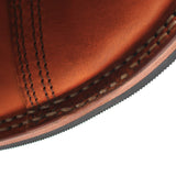 Close-up detail of a brown leather shoe corner showing double stitching, welt construction, and the edge of the sole against a white background.