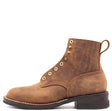 A single brown leather lace-up boot with brass eyelets, white contrast stitching, and a dark brown stacked heel, shown from a side profile on a white background. The brand name 'NICKS' is embossed on the side.