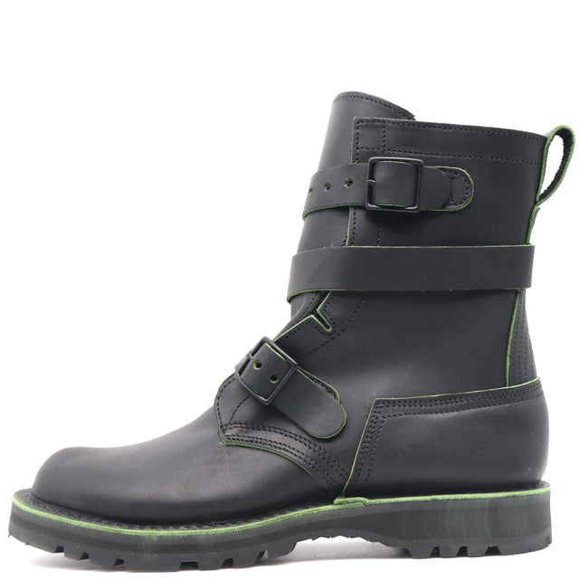 A black leather ankle boot with three adjustable straps and a rugged sole, featuring bright green contrast stitching and trim.