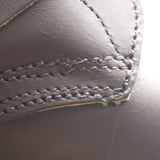 Close-up of a dark brown leather product showing detailed stitching and a slightly worn, frayed edge.