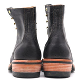 A pair of black leather lace-up boots shown from the back, featuring brass grommets and a stacked brown and black sole.