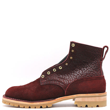 Dark red textured leather boot with brass hardware and honey lug outsole in front of a white background.