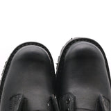 Close-up of a pair of black leather boots viewed from above against a white background. The right boot is clearly longer than the left.