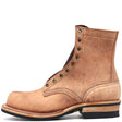 Tan boot with antique hardware in front of a white background.