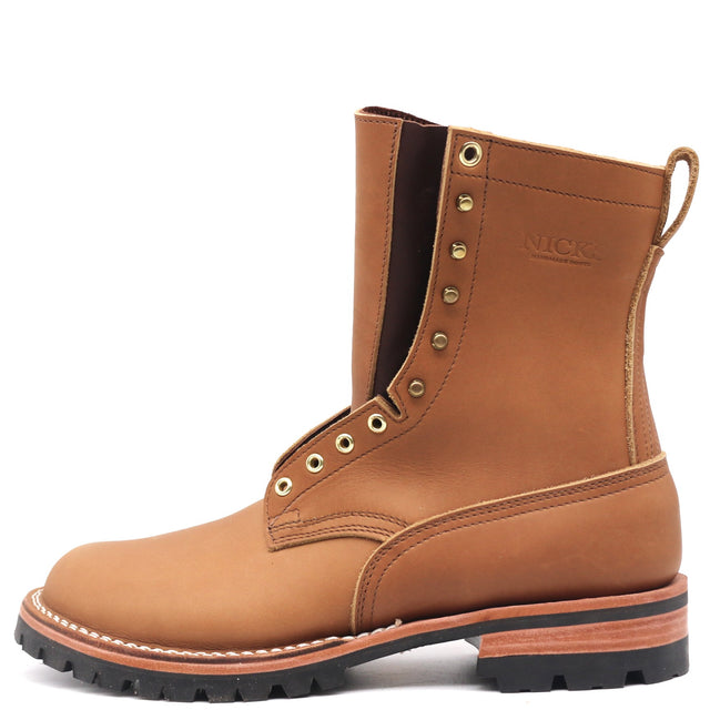 A tan leather work boot with gold-tone eyelets, a pull loop, and a black lug sole, shown from a side profile on a white background. The brand 'NICKS' is embossed on the side.