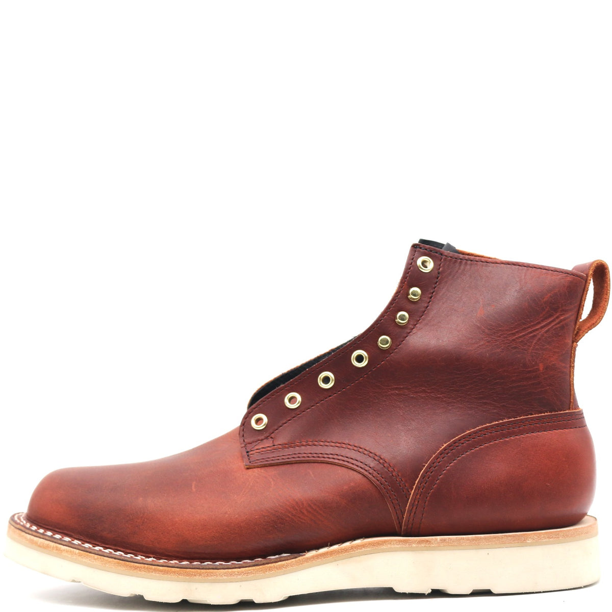 Reddish brown ankle boot with rear pull loop, brass hardware, and white wedge outsole in front of a white background.