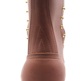 Close-up of a brown leather boot featuring decorative gold-tone studs and stitching on a white background.