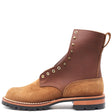 A brown leather lace-up ankle boot with a tan suede toe and heel, featuring brass eyelets, metal studs, and a black lug sole, shown from a side profile on a white background.